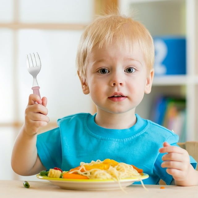 A toddler enjoying their meal with a fork from the set