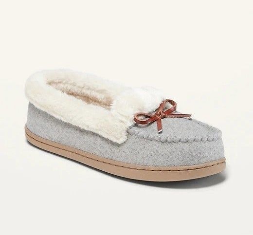A pair of grey and brown moccasin slippers with soft white faux-fur lining.