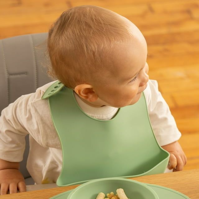 A baby wearing a colorful silicone bib during mealtime
