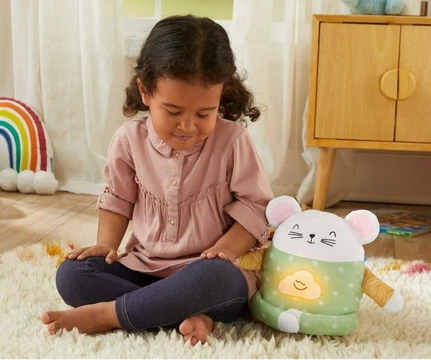 A child sitting cross-legged with eyes closed next to the plush mouse