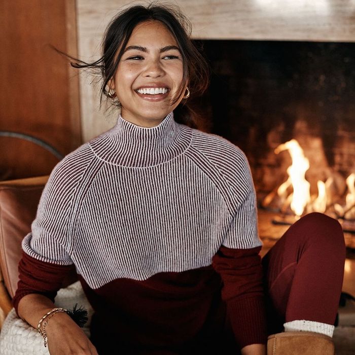 A model wearing the maroon sweater with a striped top