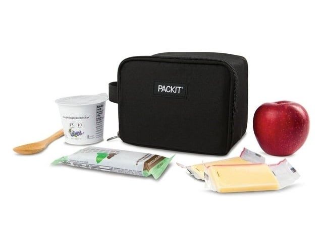 A PackIt lunch bag containing yogurt, an apple, a spoon, and snack bars, showcasing its practical food storage design.