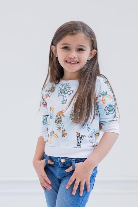 A child dressed in a playful Toy Story-themed sweatshirt
