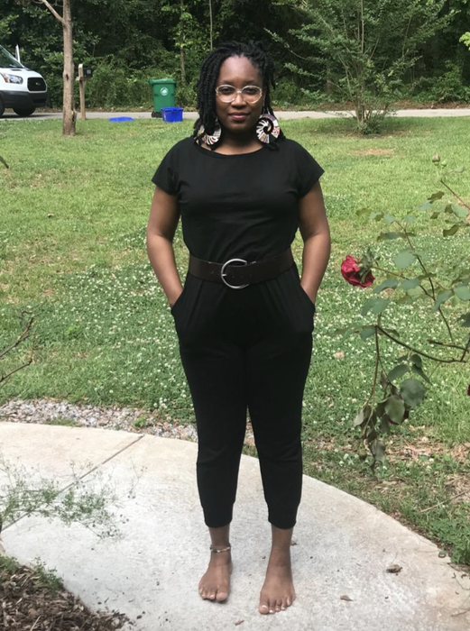 A reviewer wearing the black jumpsuit with a belt