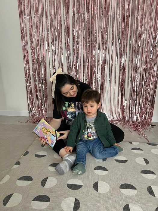 A mother and child sitting together on a colorful rug, enjoying a book