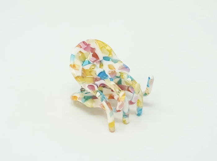 Close-up of a mini claw clip featuring a white base with red, pink, yellow, and blue speckles