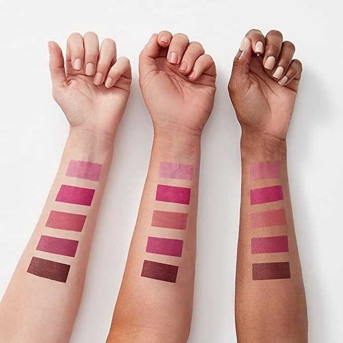 Three models with varying skin tones showcasing swatches of a pink lipstick