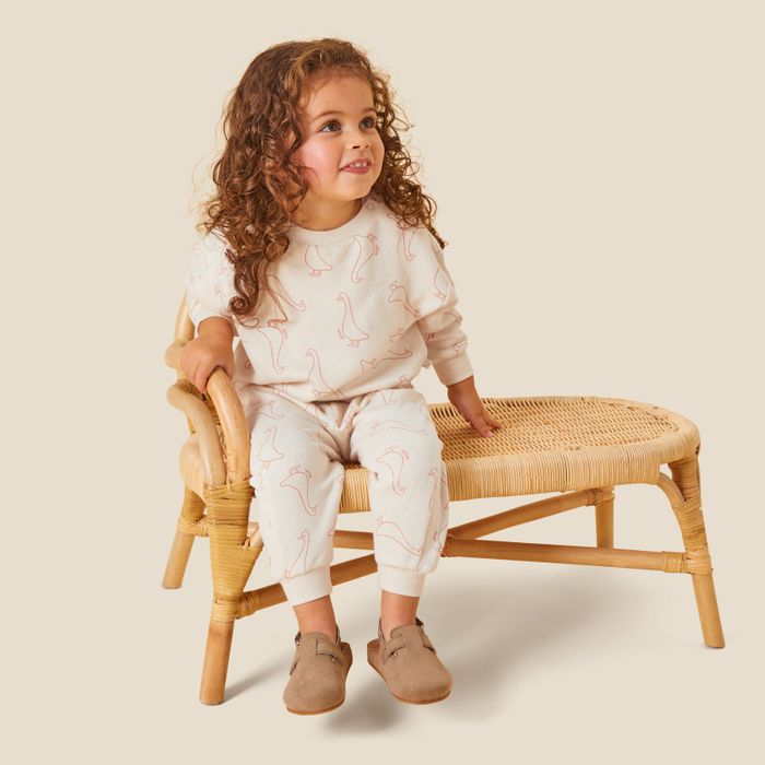 A little girl wearing an off-white sweat set with pink duck designs