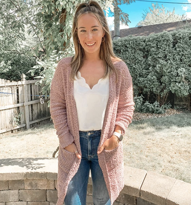A reviewer wearing a pink sleeved midi-length cardigan with pockets