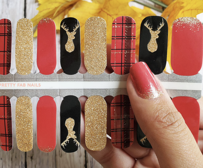 model holding a collection of holiday nail wraps in red, glittery gold, black, and checkered designs