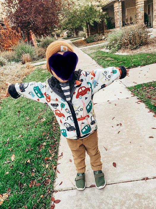 A reviewer’s child wearing a fleece zip-up jacket with car designs