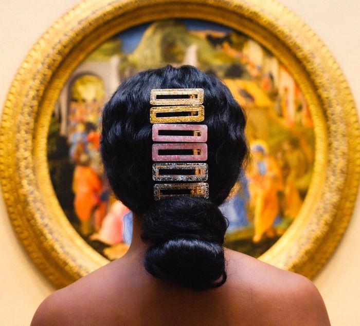A model with six clips styled above a low bun: two gold, two pink, and two silver