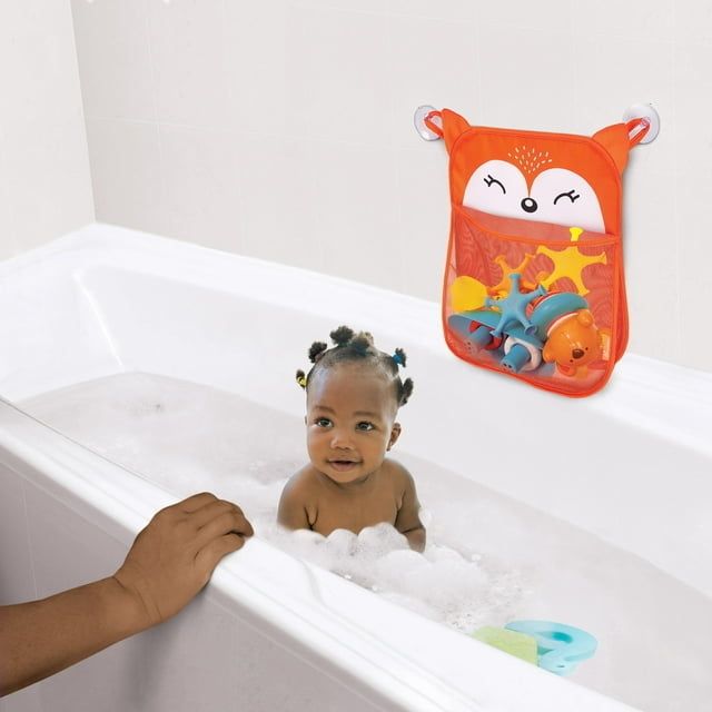 A child enjoying their bath with a bath toy drying bag hanging on the wall