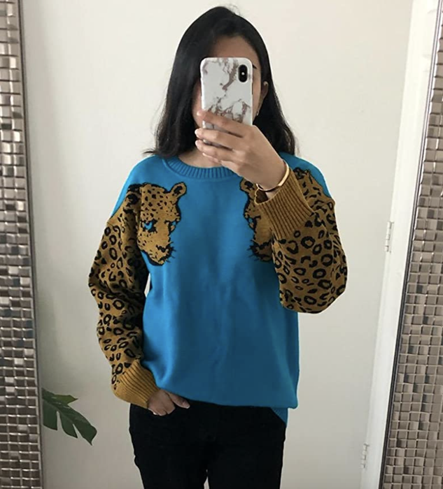 reviewer showcasing the blue sweater adorned with leopard print on the sleeves
