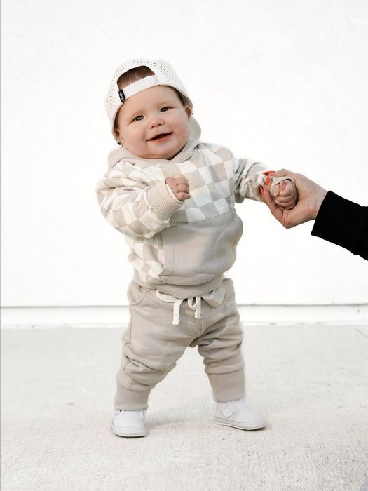 A child model in a tan checkered hoodie and coordinating joggers