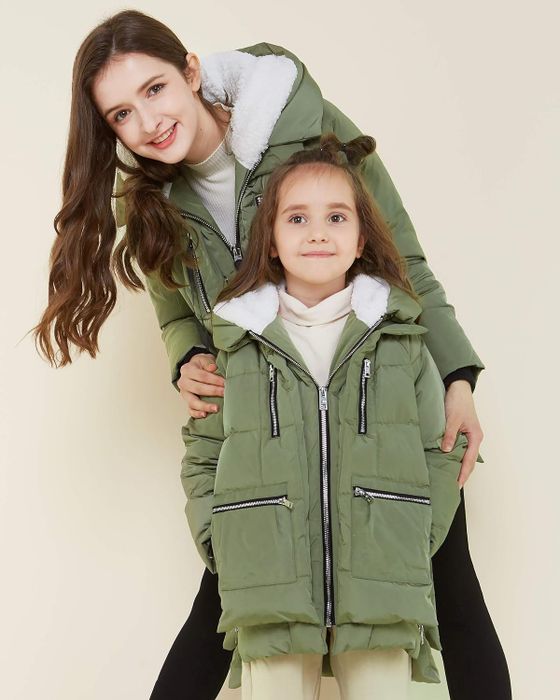 A tween and a child wearing matching green Oralay coats.