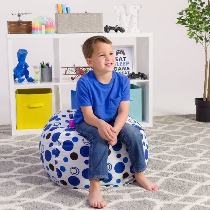 a child model sits on a chair filled with plush toys