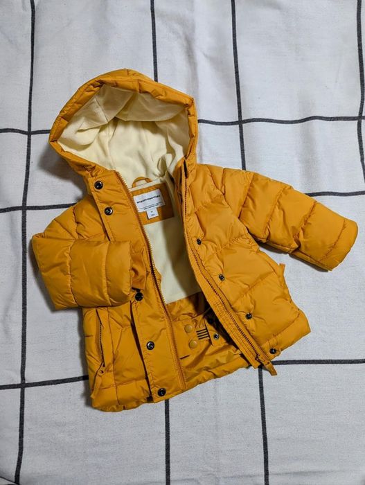 A reviewer’s child wearing a vibrant mustard yellow winter coat