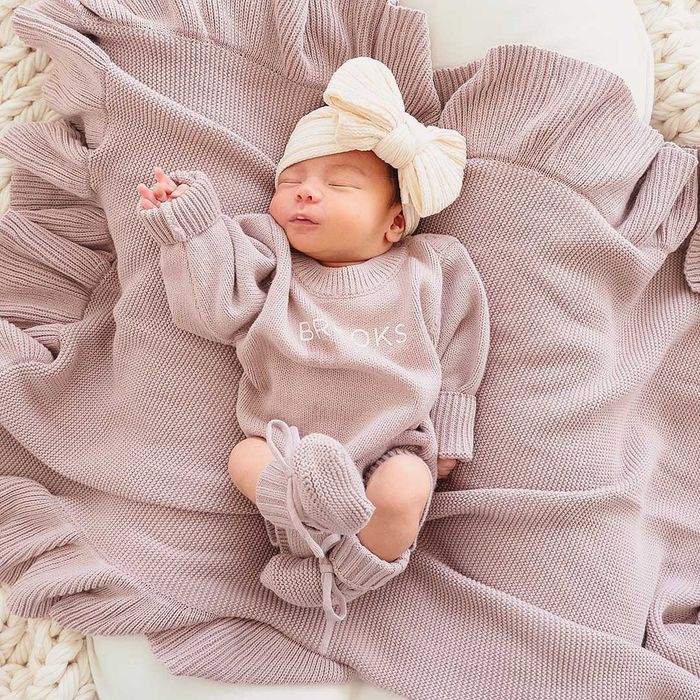 An infant wearing a lavender personalized sweater romper