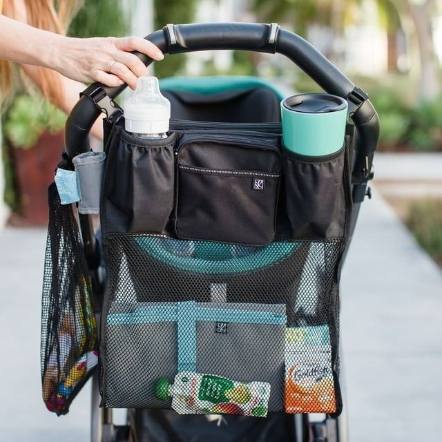 A stroller organizer featuring multiple pockets holding a bottle, cup, and snacks, with no people visible.