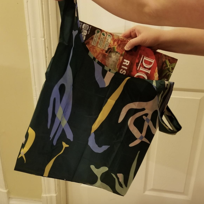 A reviewer photo of a pizza box being placed in the bag