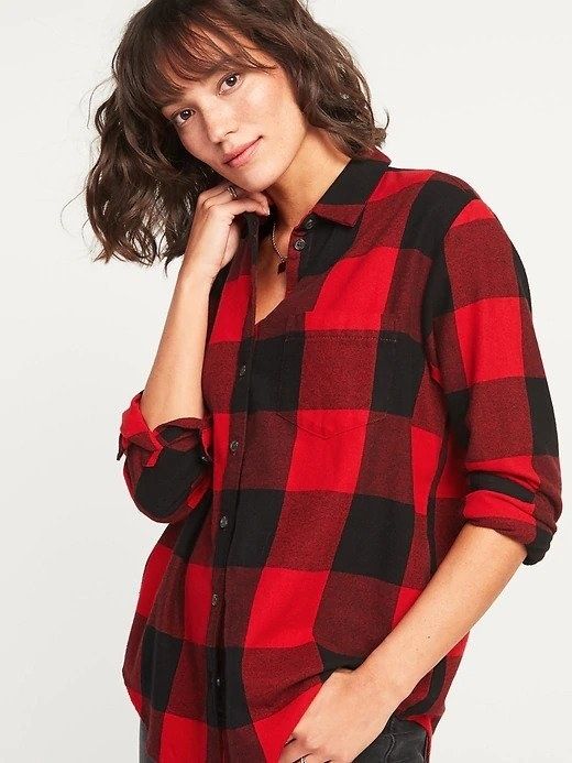 A woman dressed in a large black and red plaid flannel shirt.