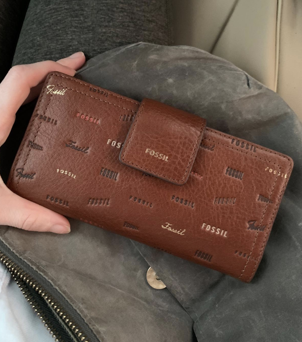 A reviewer holding the brown patterned wallet with a clasp
