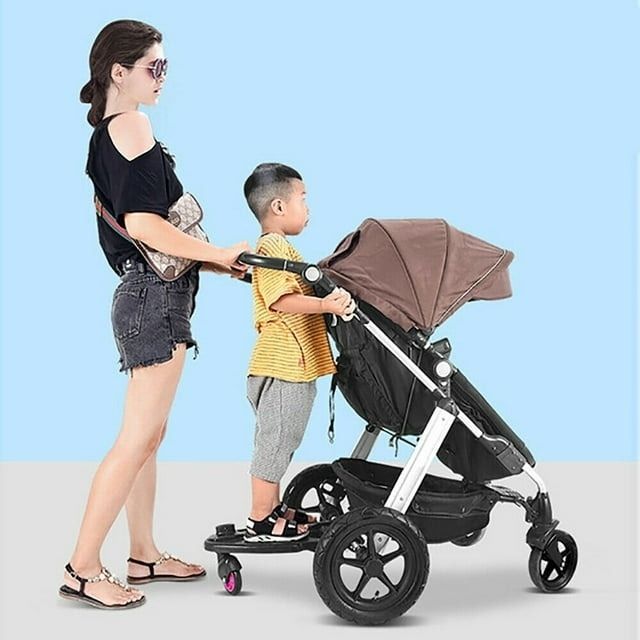 A woman pushing a stroller designed for both an infant and a standing child, both dressed casually. Perfect for family outings.