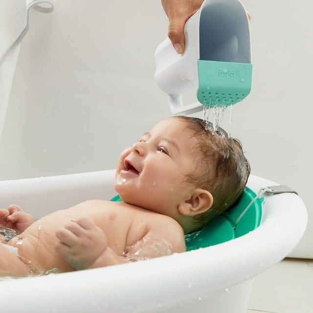 A baby getting their hair washed with a shower cup during bathtime