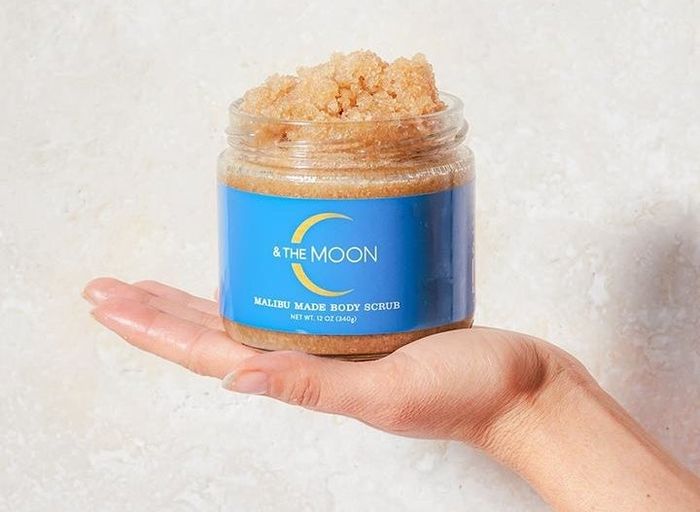 A hand holding a jar of the body scrub.