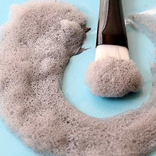 A gray foaming mask placed beside a brush