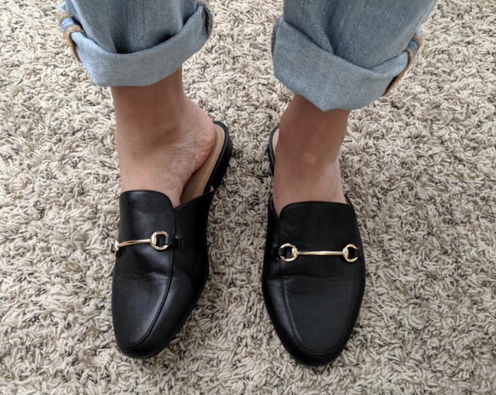 reviewer showcasing the black loafers with a gold chain detail