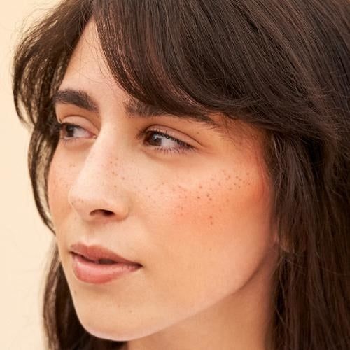 A model wearing Freck on their cheeks and nose, showcasing natural-looking freckles.