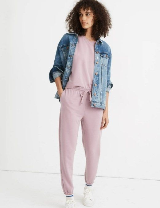 model showcasing the joggers in light purple, paired with white sneakers, a matching top, and a denim jacket