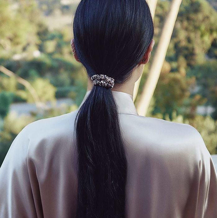 A model is wearing a slip scrunchie to secure their ponytail.