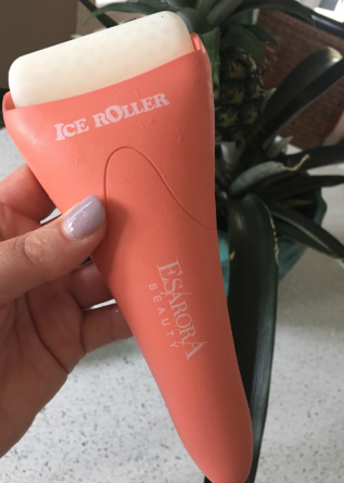 A reviewer holding the ice roller with a base in a soft salmon color.
