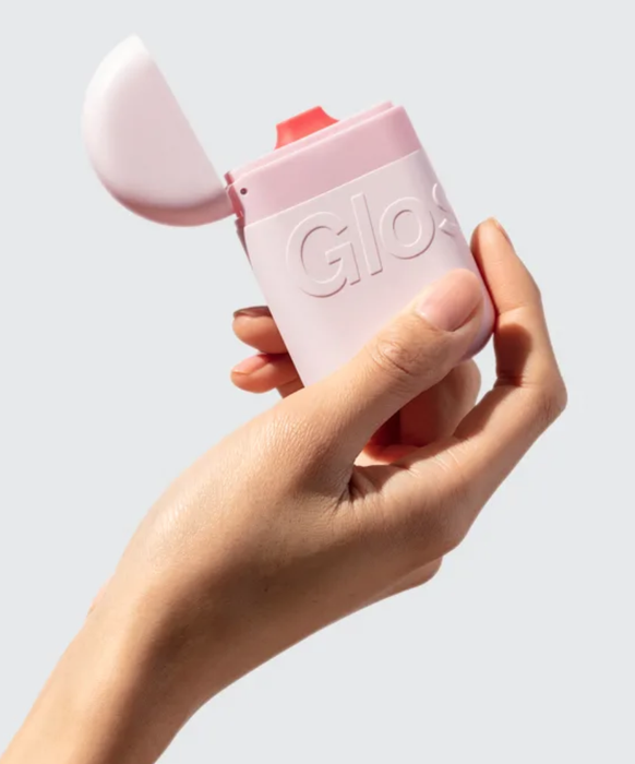 a model holding a pink, rounded container with a flip-top cap