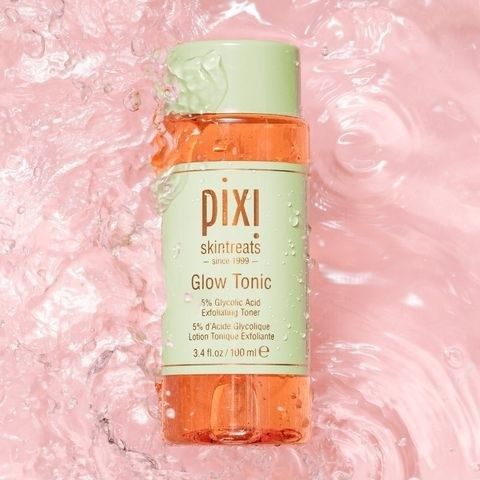 The bottle of Glow Tonic displaying the orange liquid inside with a green logo on the bottle.