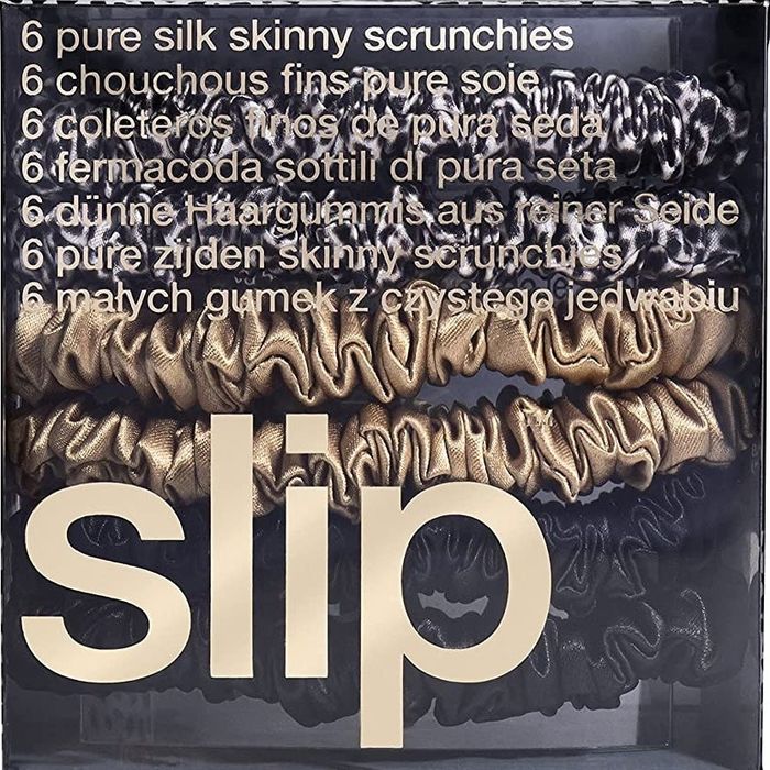 A set of four slip scrunchies packaged in their sleek black packaging.