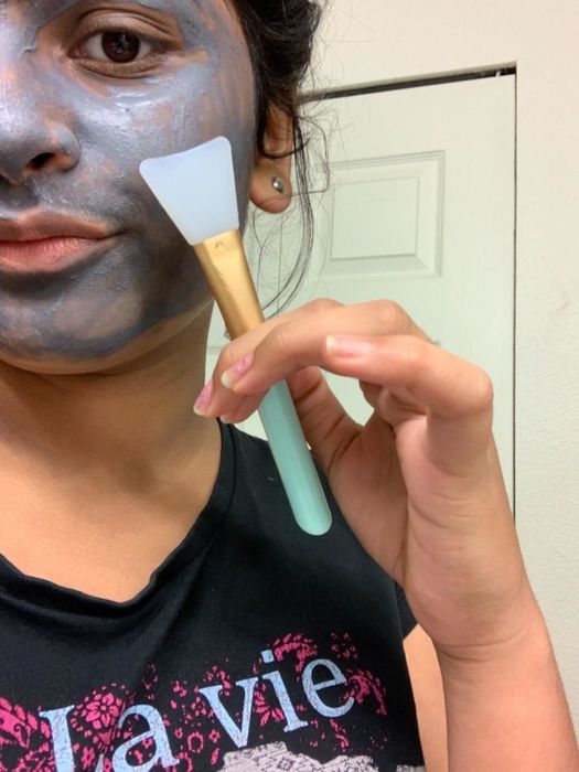 a reviewer holding the mint green handle of a face mask spatula