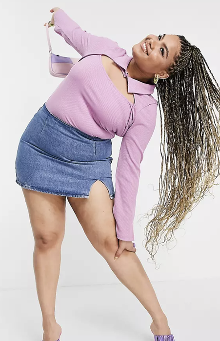 model styling a ribbed collar cutout top paired with a denim skirt