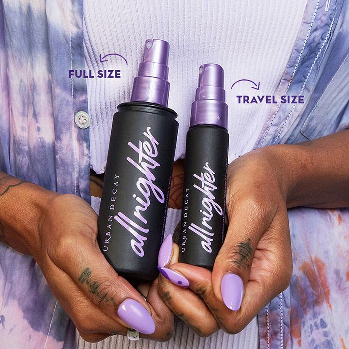 A model is holding one full-size bottle and one travel-size bottle of the setting spray, with arrows pointing to each.