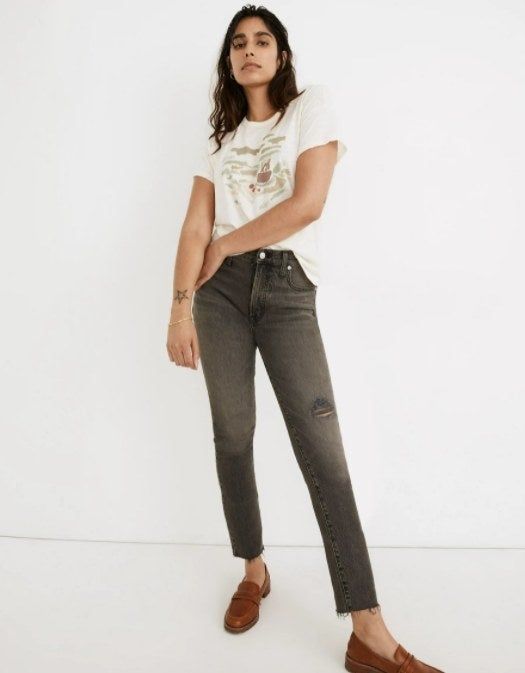 model styling gray vintage-wash jeans with brown loafers and a graphic tee