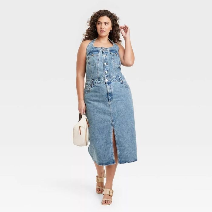 The model is wearing a mid-length denim dress featuring a front slit.
