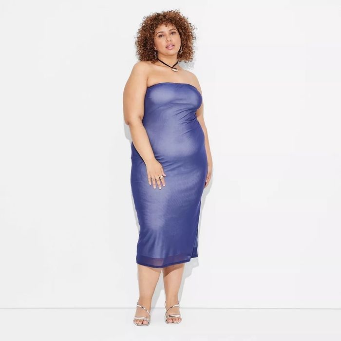 The model is seen wearing a strapless, form-fitting dress and high heels.