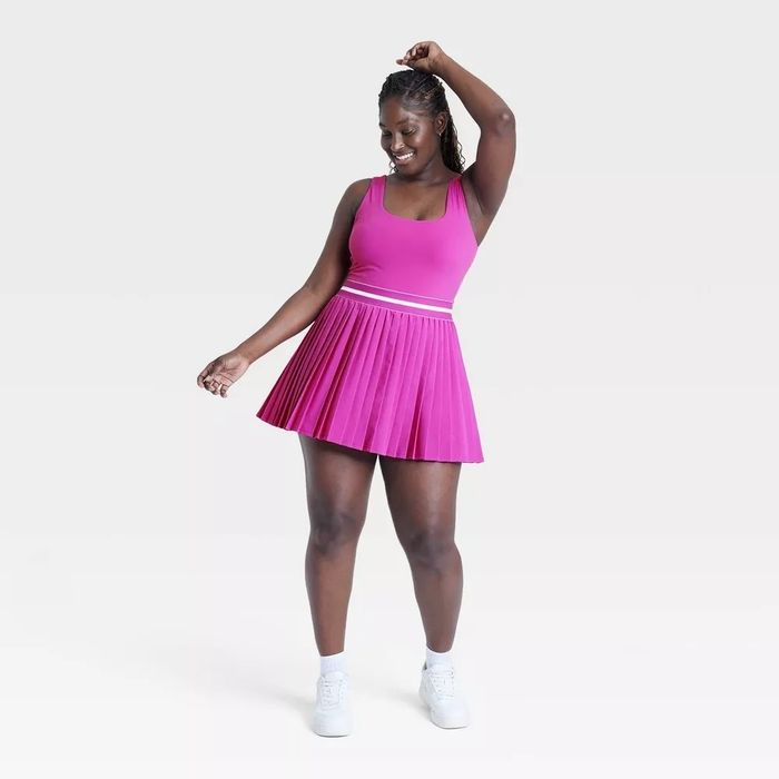 The model is wearing a sleeveless athletic dress featuring a pleated skirt.