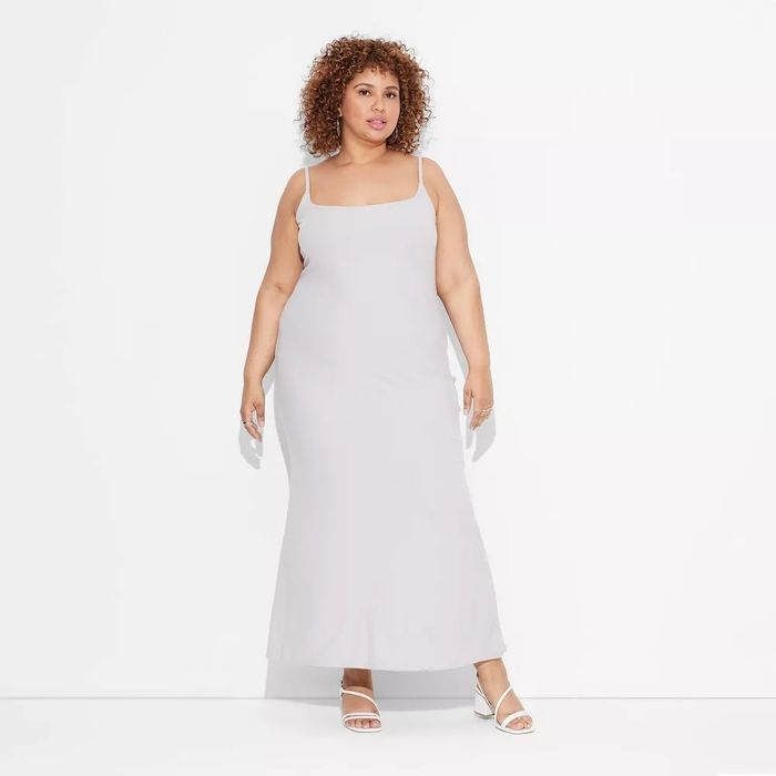 The model is dressed in a sleeveless maxi dress paired with sandals.