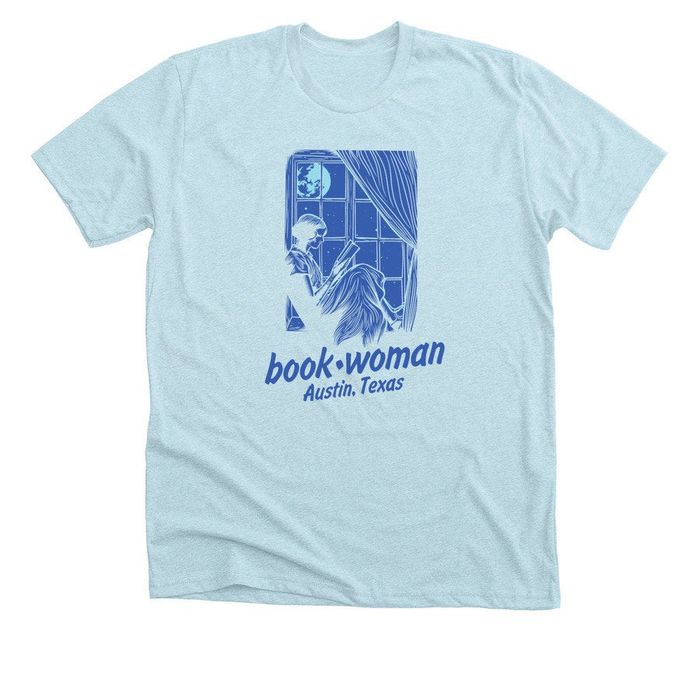 A T-shirt with an illustration of a woman reading under moonlight, from the store Book Woman in Austin, Texas