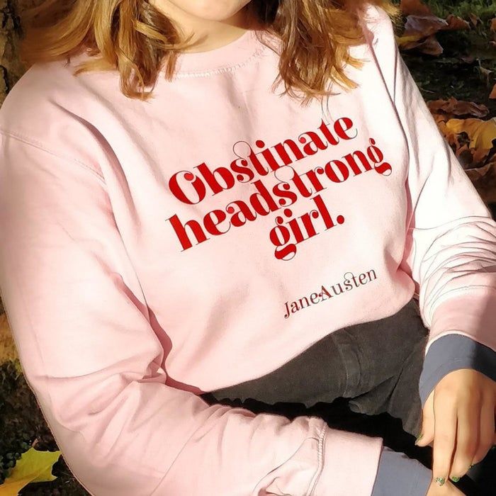 A model wearing the pink sweatshirt with red lettering
