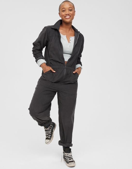 Model dressed in a grey long-sleeve jumpsuit with a center zipper and cuffed pants.